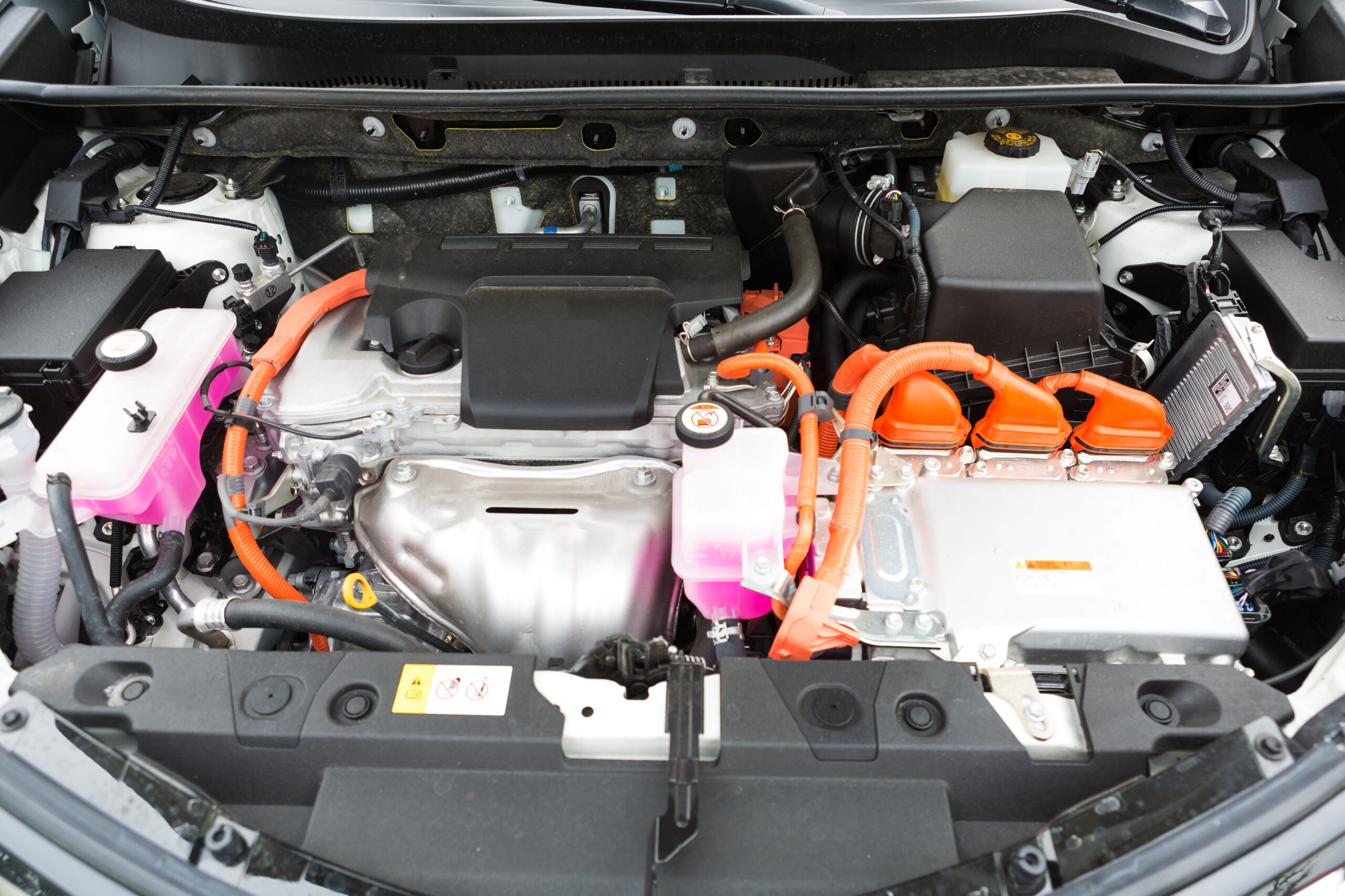 The interior of a hybrid car. The battery is located on the right side and has bright orange connectors.