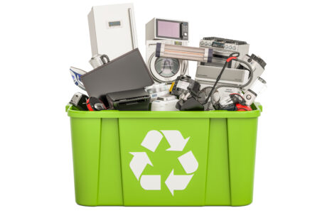 A green recycling bin with a bunch of electronics in it